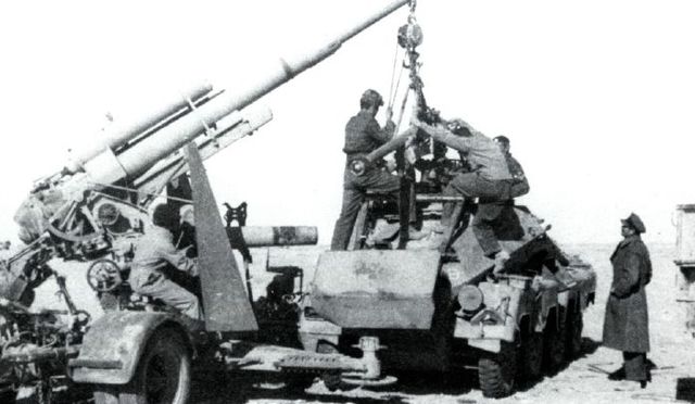 Ingenieros y mecánicos usan un 88 mm alemán capturado como grúa para levantar el arma de lo que parece ser un vehículo blindado alemán de 8 ruedas también capturado