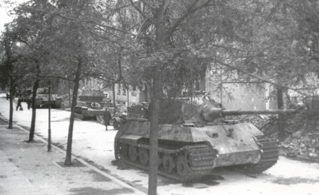 En primer plano un Tiger II puesto fuera de combate durante la batalla de Berlín. Detrás un Flakpanzer Wirbelwind y un Panzer V Panther
